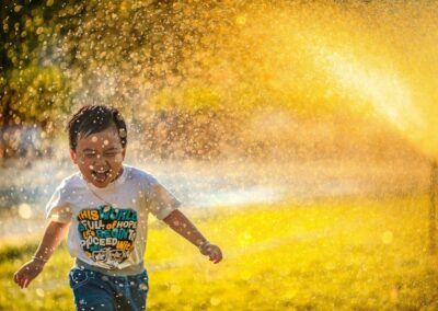 a young boy running through a sprinkle of water